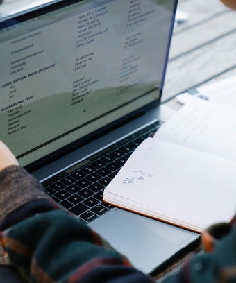 Einzelperson beim Individualcoaching vor einem Laptop mit fachlichen Inhalten, Notizbuch mit handschriftlichen Skizzen daneben. persönliche Lernbegleitung, Mentoring oder 1:1 Coaching in einer ruhigen Umgebung.