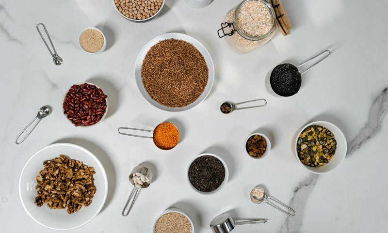 A colorful arrangement of various rice types, beans, and spices displayed together, highlighting their diverse textures and rich hues.