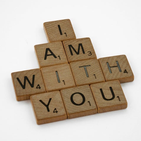 Scrabble tiles laid out to depict the words I am with you.