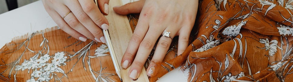 A focused view of hands measuring fabric, an essential step in garment making or upholstery.