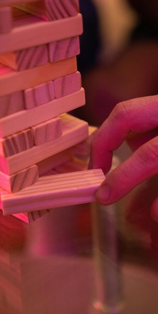 Fingers removing bricks from jenga tower.