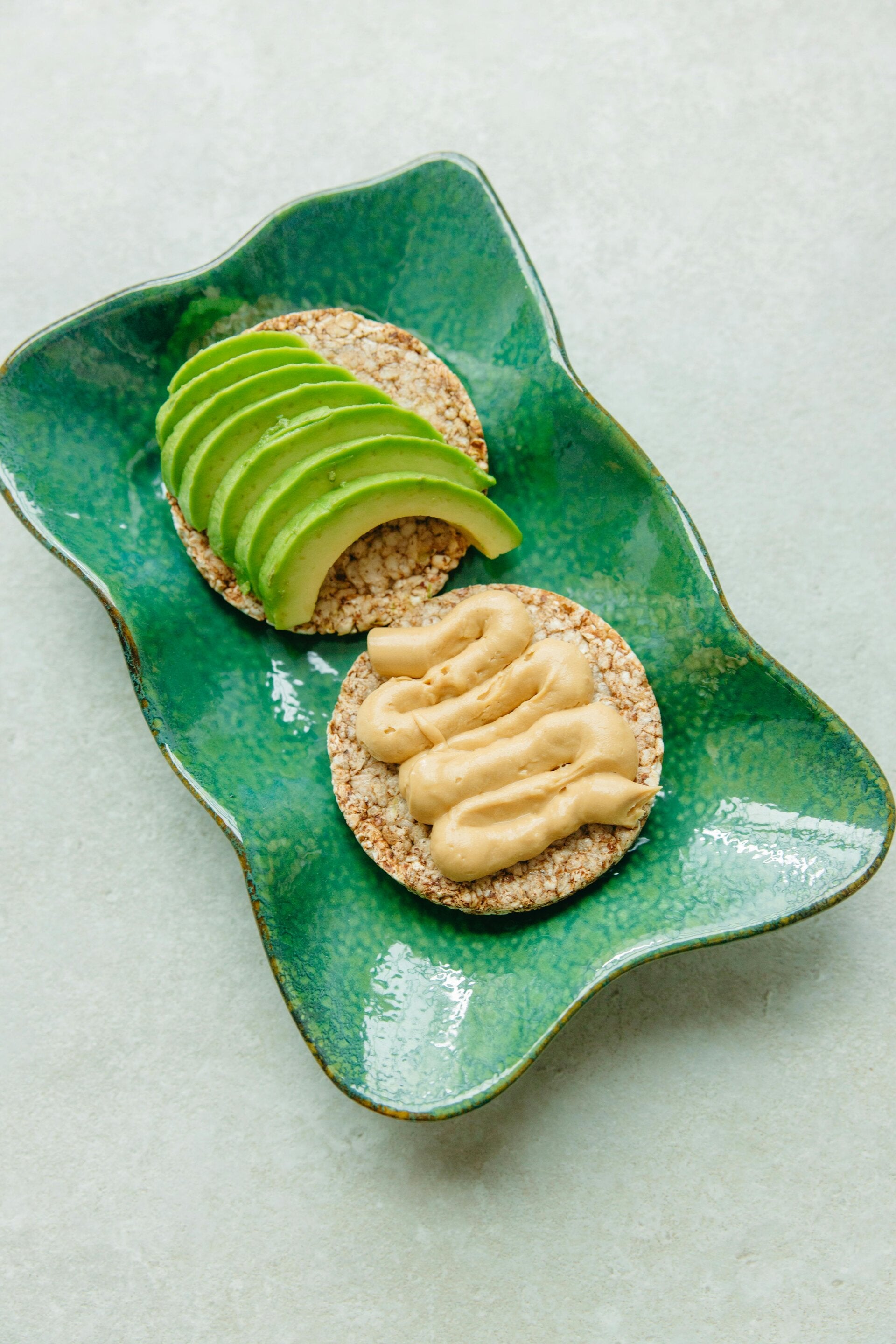 creamy, pale-yellow Dijon dressing with a whisk, ready to be served on a cracker with another cracker topped with avocado