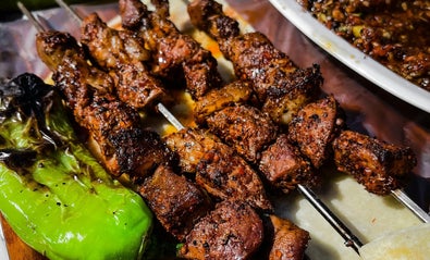bunch of kebab skewers next to a grilled pepper