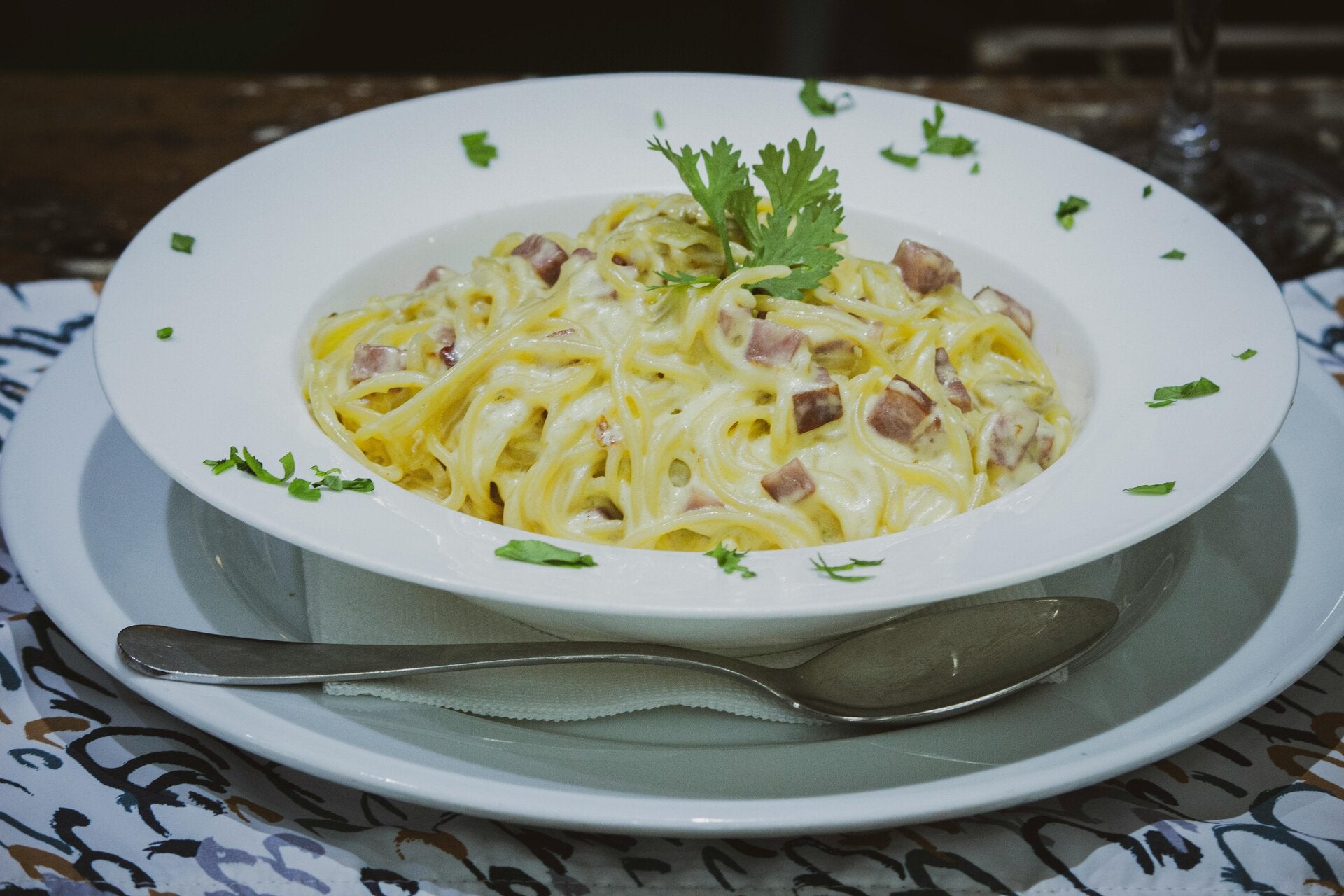 Ein Teller mit Spaghetti Carbonara, cremig und reichhaltig, garniert mit frischem Pfeffer und Petersilie.