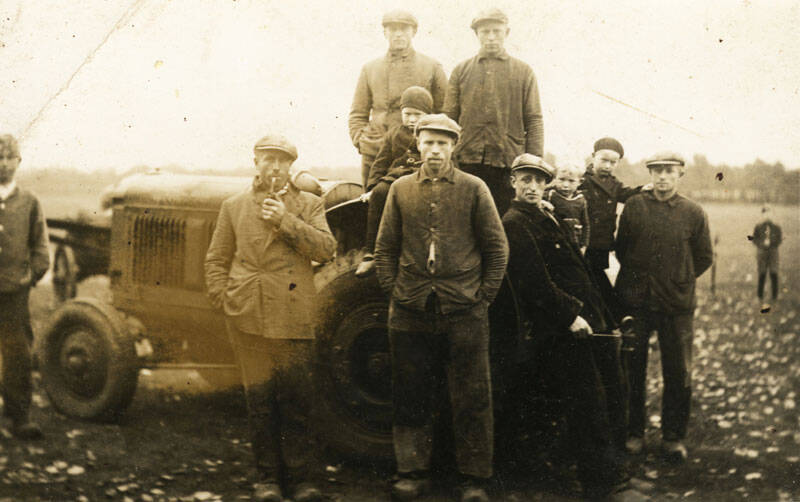 Groep mannen bij landbouwtractor