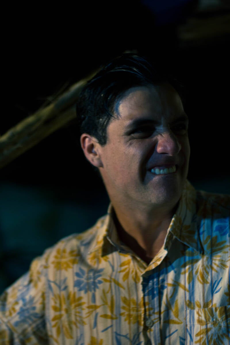 Portrait of an actor in a patterned shirt against a dark background