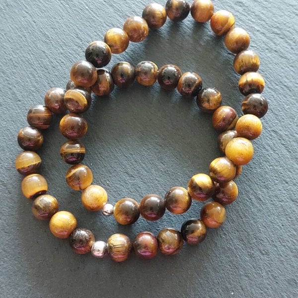 Geelbruine Tijgeroog armband met 8 mm kralen en een zilveren kraal