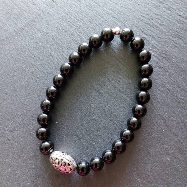 Onyx armband met een centrepiece van een grote tinnen kraal en een zilveren kraal