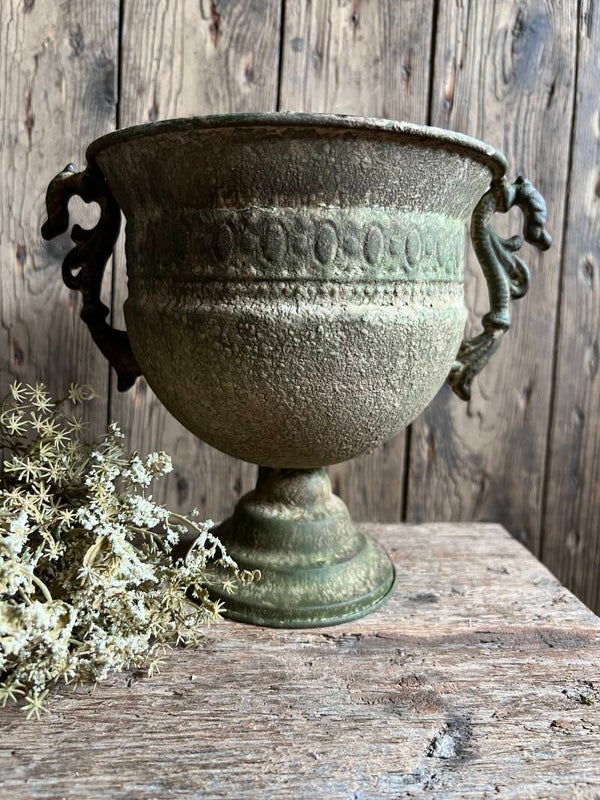 Verweerde metalen pot op voet