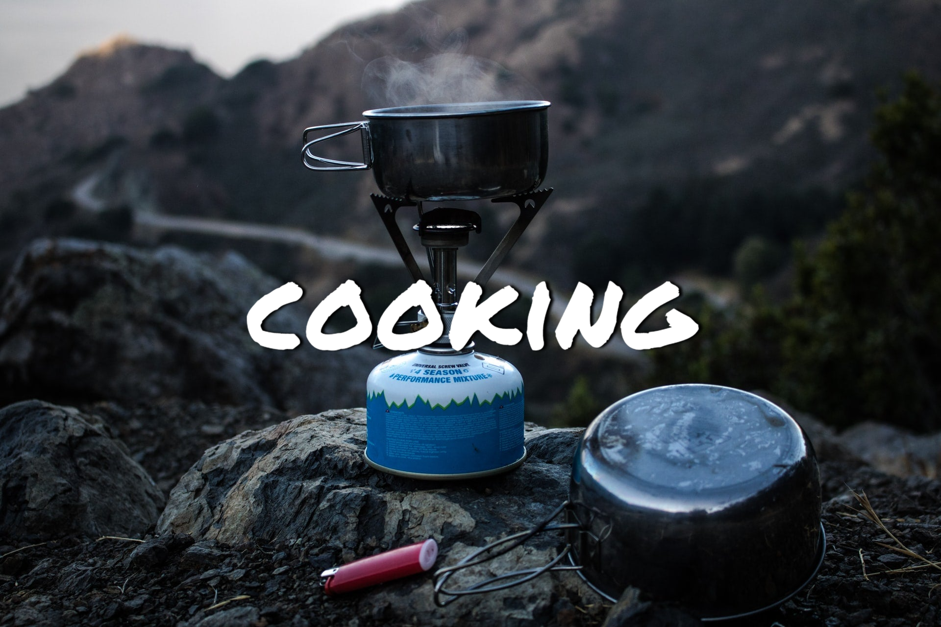 Camp style propane stove sitting on a rock in the mountains.