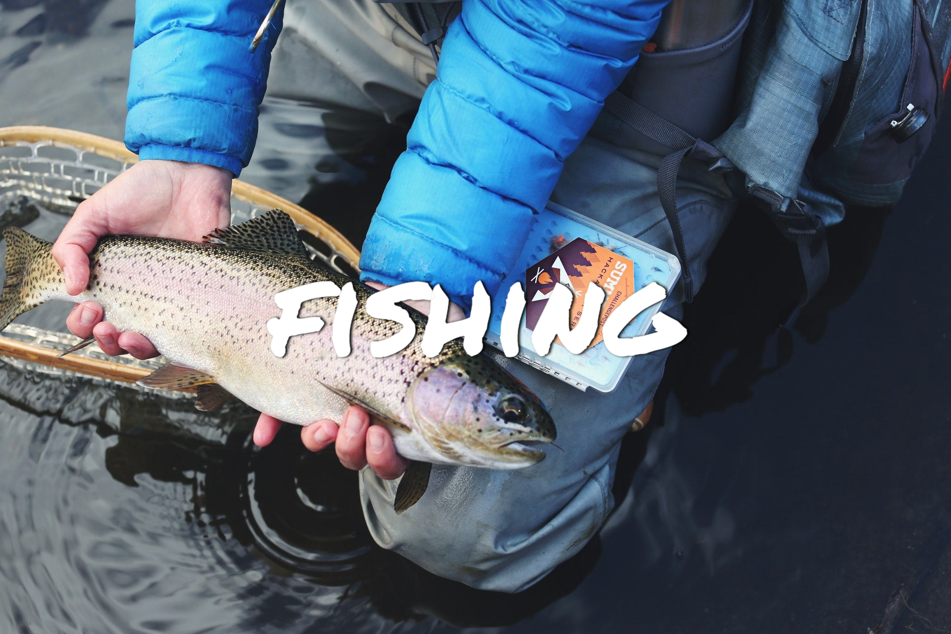 Man holding a trout in a creek after he netted it.