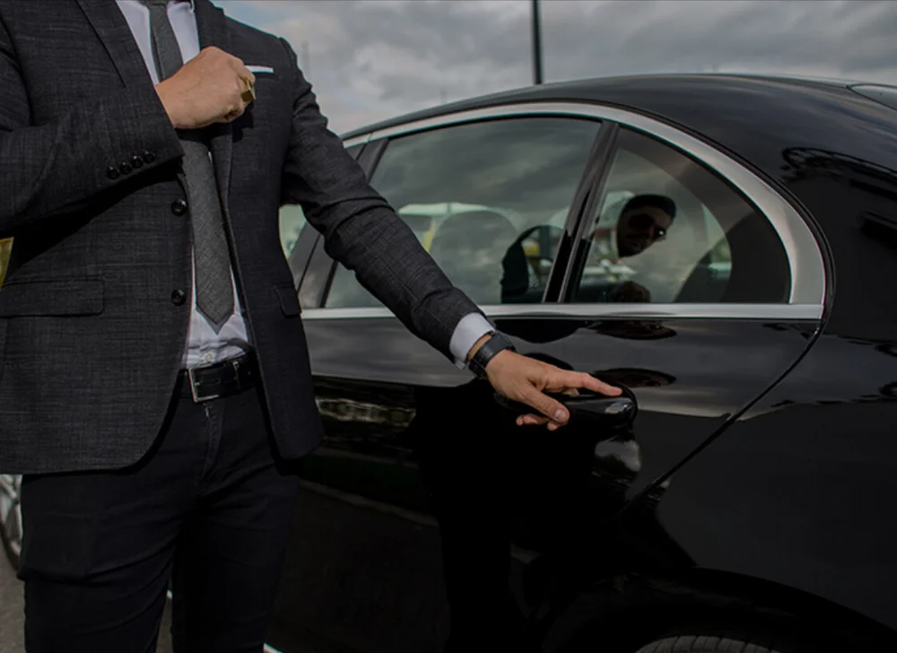 Chauffeur VTC en costume ouvrant la portière d'une berline noire — formation VTC à Le Mesnil-en-Thelle (Oise (60)) chez BYS Formation 60