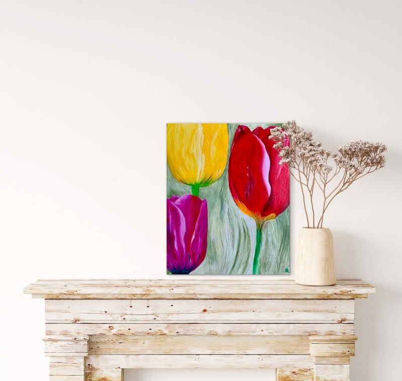 Boven sidetable hangt tegen een witte muur een in olieverf geschilderde figuratieve afbeelding van drie tulpen