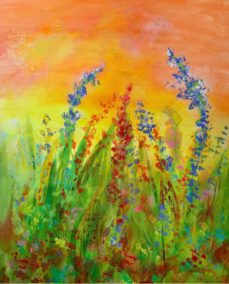 tegen de achtergrond van een door de opkomende zon oranje gekleurde lucht staan bloemen en grassen