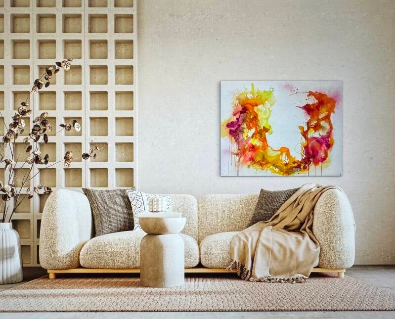 Bij de witte zithoek hangt een kleurrijk abstract schilderij.