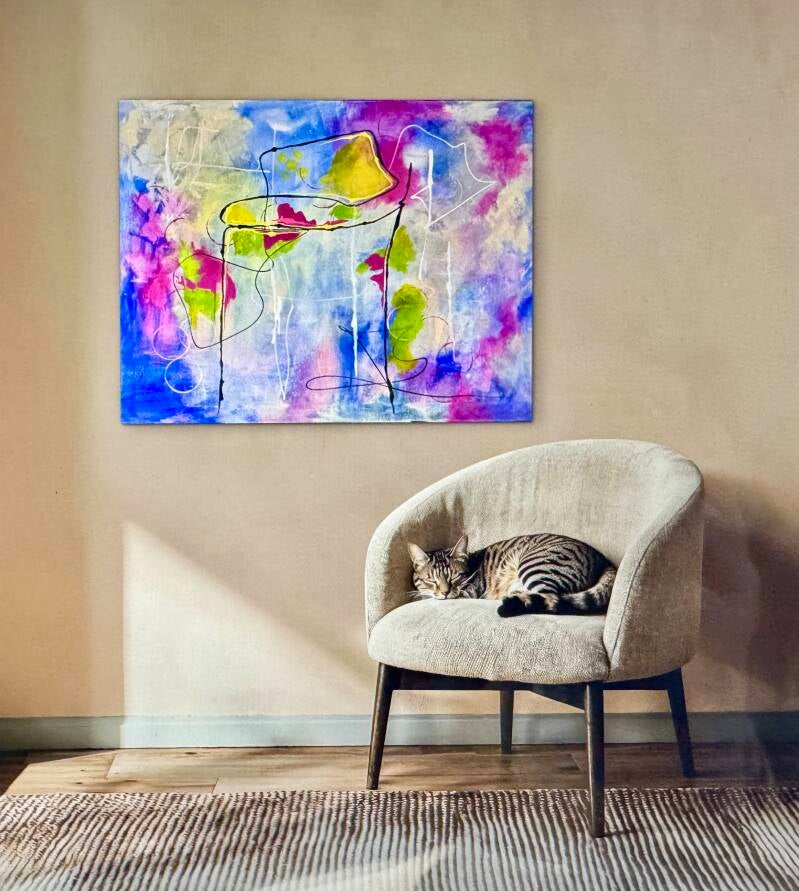 In het interieur staat een stoel en aan de wand een kleurrijk abstract schilderij.