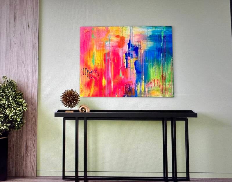 Boven de sidetable hangt een kleurrijk abstract schilderij.