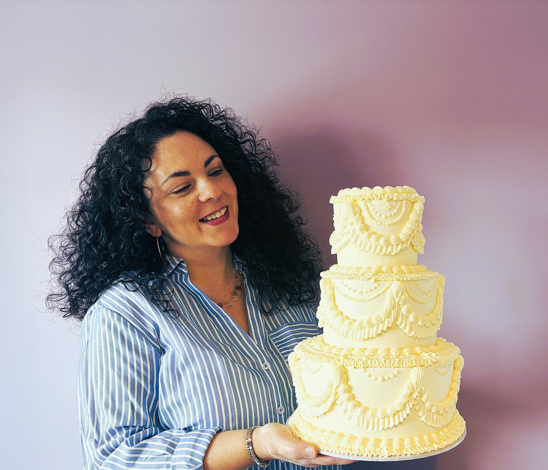 Jen, owner of Spone & Slice, holding a 3 tier  vintage wedding cake.