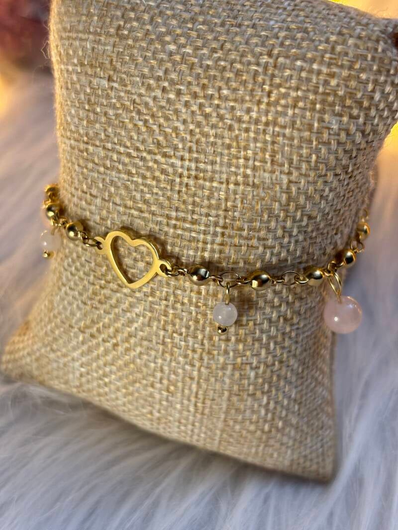 Bracelet doré avec perles en pierres naturelles, présenté sur un coussin tissé dans une ambiance douce et spirituelle
