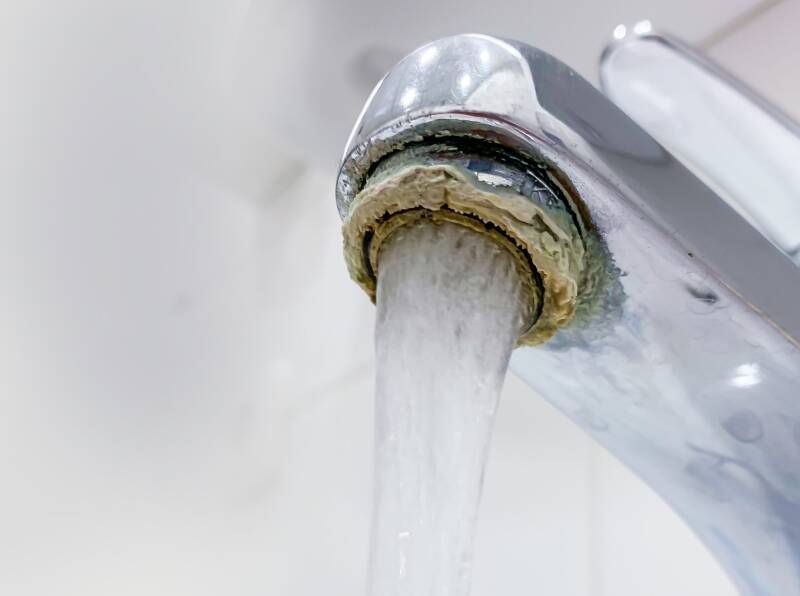 Kraan met witte kalkaanslag rond de perlator.