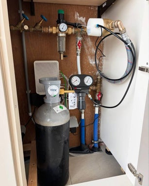 SoluCalc CO₂-waterontharder netjes ingebouwd in kast, aangesloten op de waterleiding