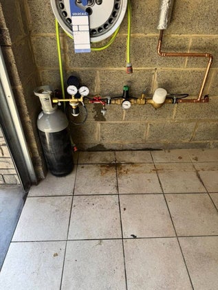 Installatie van SoluCalc waterontharder met koperleidingen, drukregelaar en CO₂-fles in garage