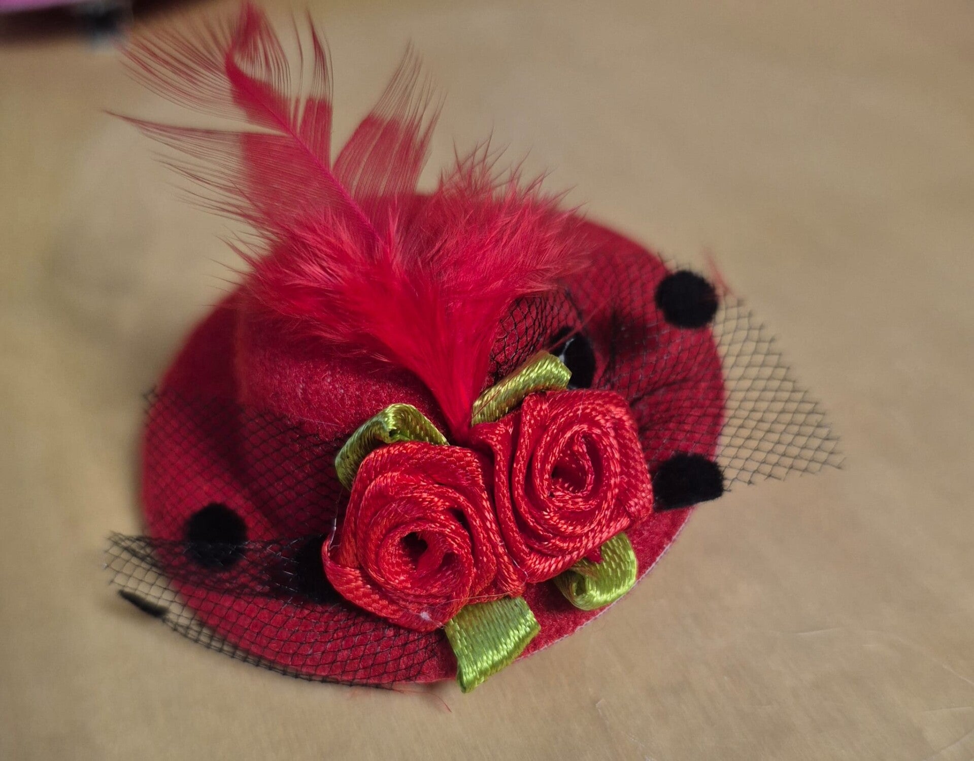 Elegante, rode minihoedje met roosjes, veertjes en lintjes. Voor in het haar of als broche.