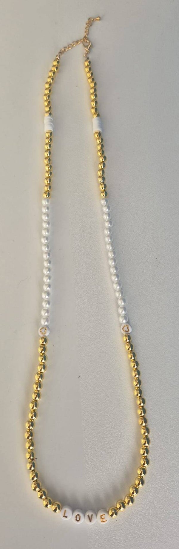 Mooie ketting met goudkleurige kralen, witte parels, hartjes en de tekst LOVE.