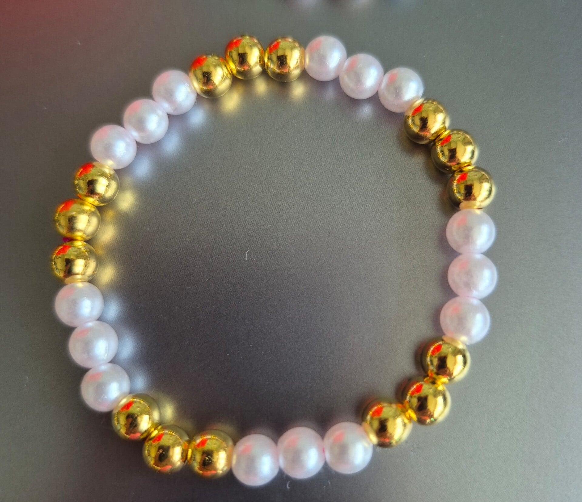 Mooie armband voor kinderen met witte en gouden kralen.