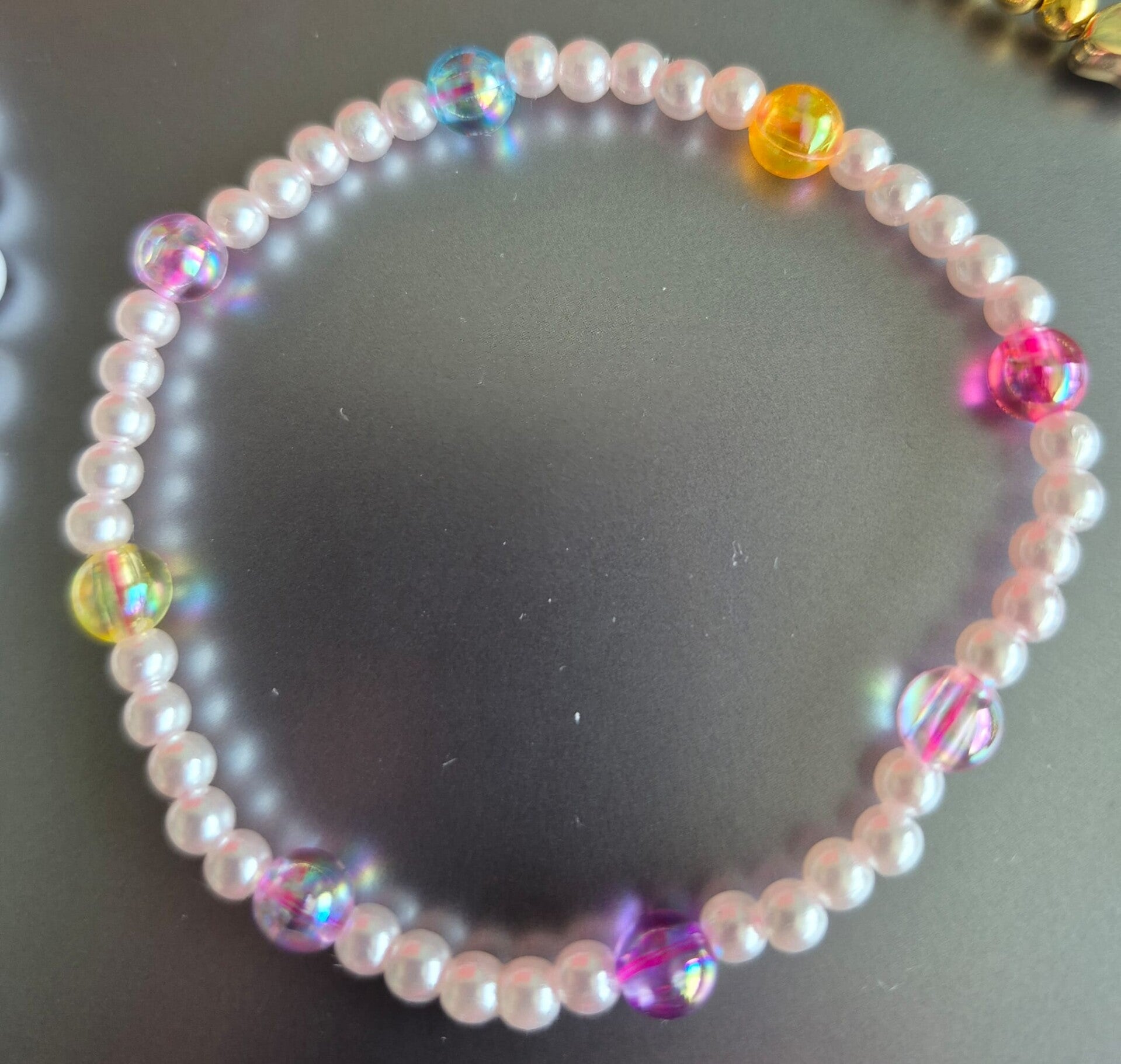 Mooie kinderarmband met leuke witte kralen en gekleurde balletjes.