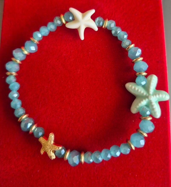 Mooie zeester armband met blauwe kralen en gouden details.