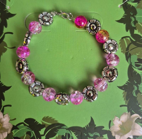 Prachtige armband met roze kralen en zilverkleurige bloemetjes.