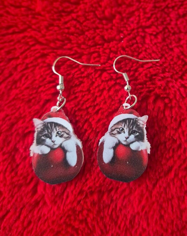 Leuke oorbellen met een katje met een kerstmuts op, op een rode kerstbal.