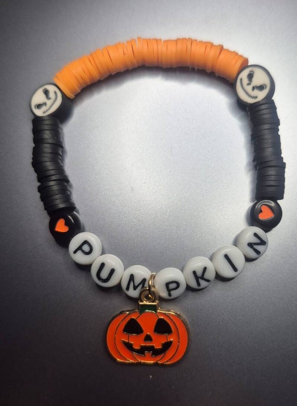 Halloween-armband met pompoenhangertje, hartjes en oranje, zwarte en witte kralen.