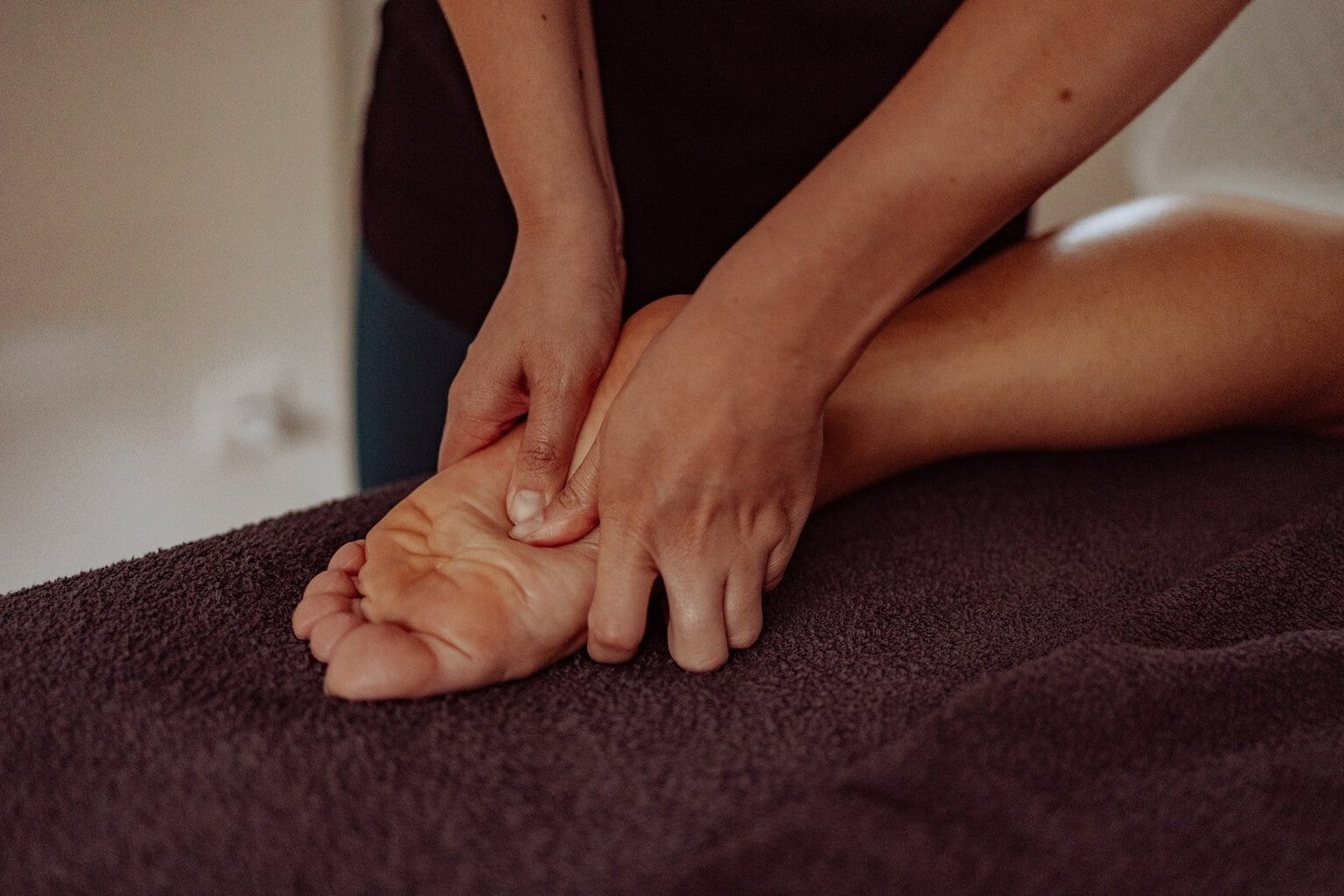 Marine, la masseuse, effectue des pressions sous le pied avec ses pouces