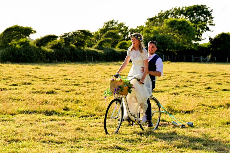 couple riding a bike a festival style wedding 