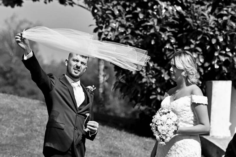 the groom playing with the brides veil