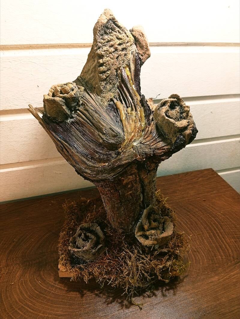 Künstlerische Skulptur, gold schimmernde Betonkunst auf Naturholz