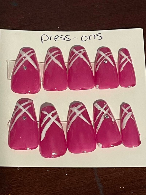 Beautiful pink coffin nails with delicate white lines and rhinestones on each thumb and ring finger.