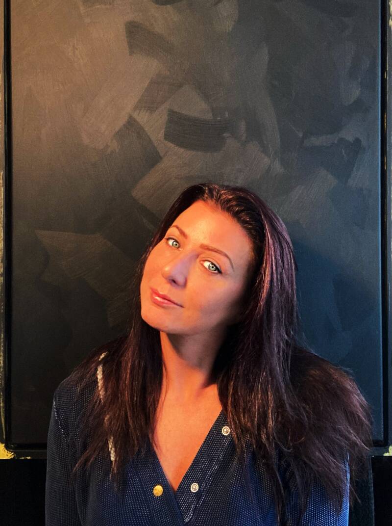 Portrait of The Artist Lezz from Lezz Arts before a black abstract painting