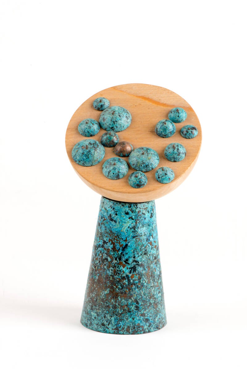 Halve bolletjes gepatineerd koper op een houtenschijf.  Het beeld is geinspireerd op de bloeiwijze van compositae. Oorbellen in de vorm van een ellipsvormigblad en waterdruppel. Goud. Handgemaakt  door  Marlies van Velzen.