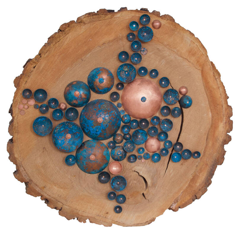 Halve bollen gepatineerd koper  (kleur blauw)  en niet gepatineerd koper op een 'schijf' uit een boomstam.  Het beeld is geinspireerd op de manier waarop mos op hout groeit. Oorbellen in de vorm van een ellipsvormigblad en waterdruppel. Goud. Handgemaakt 