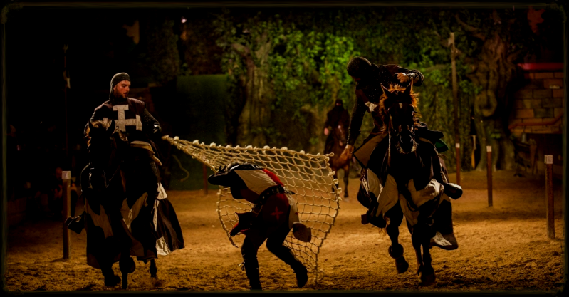 torneo medieval ,un caballero siendo atraapdo por una red que controla dos jinetes