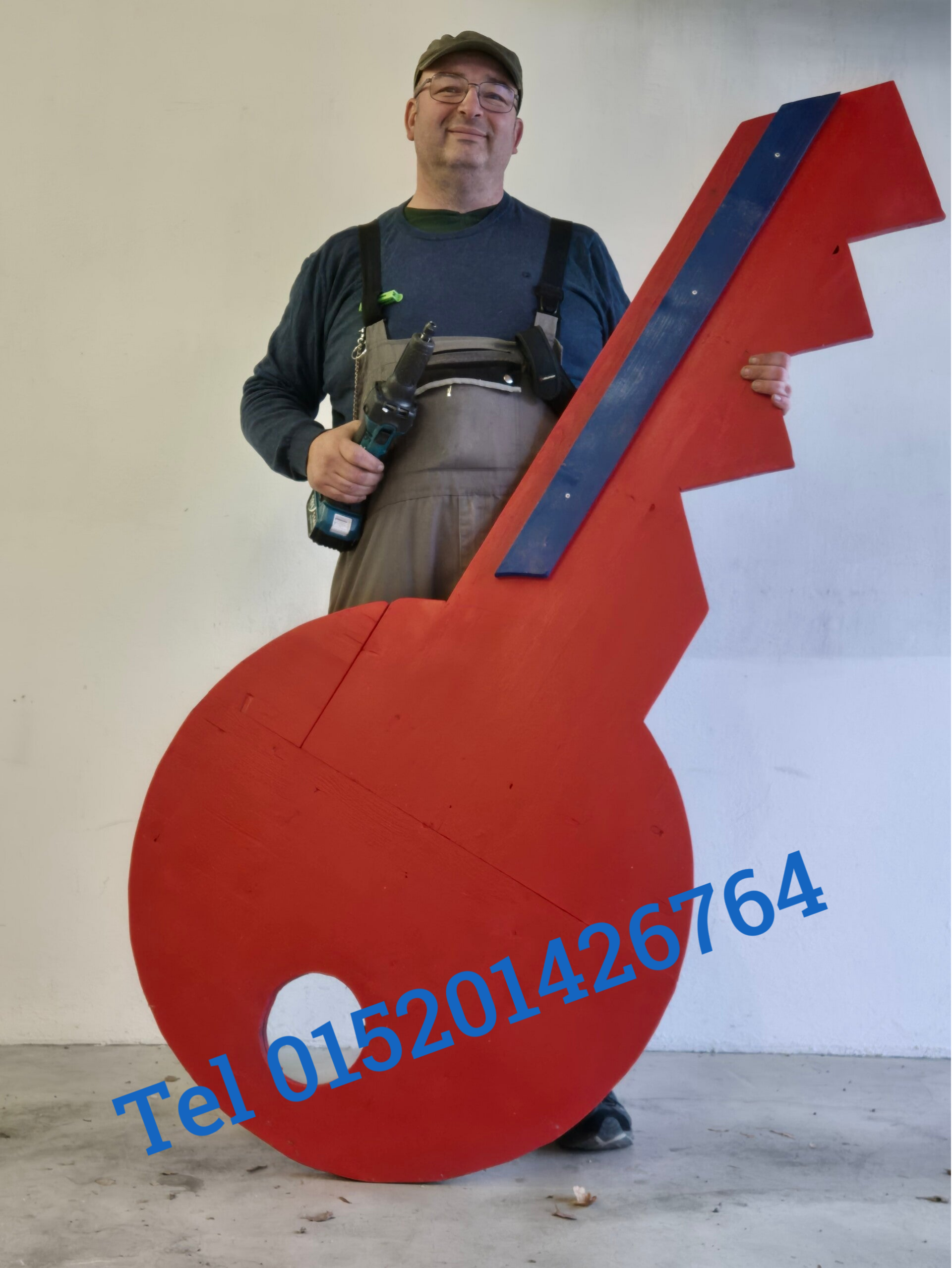 Handwerker der einen übergrosen roten Schlüssel aus Holzin der Hand hält