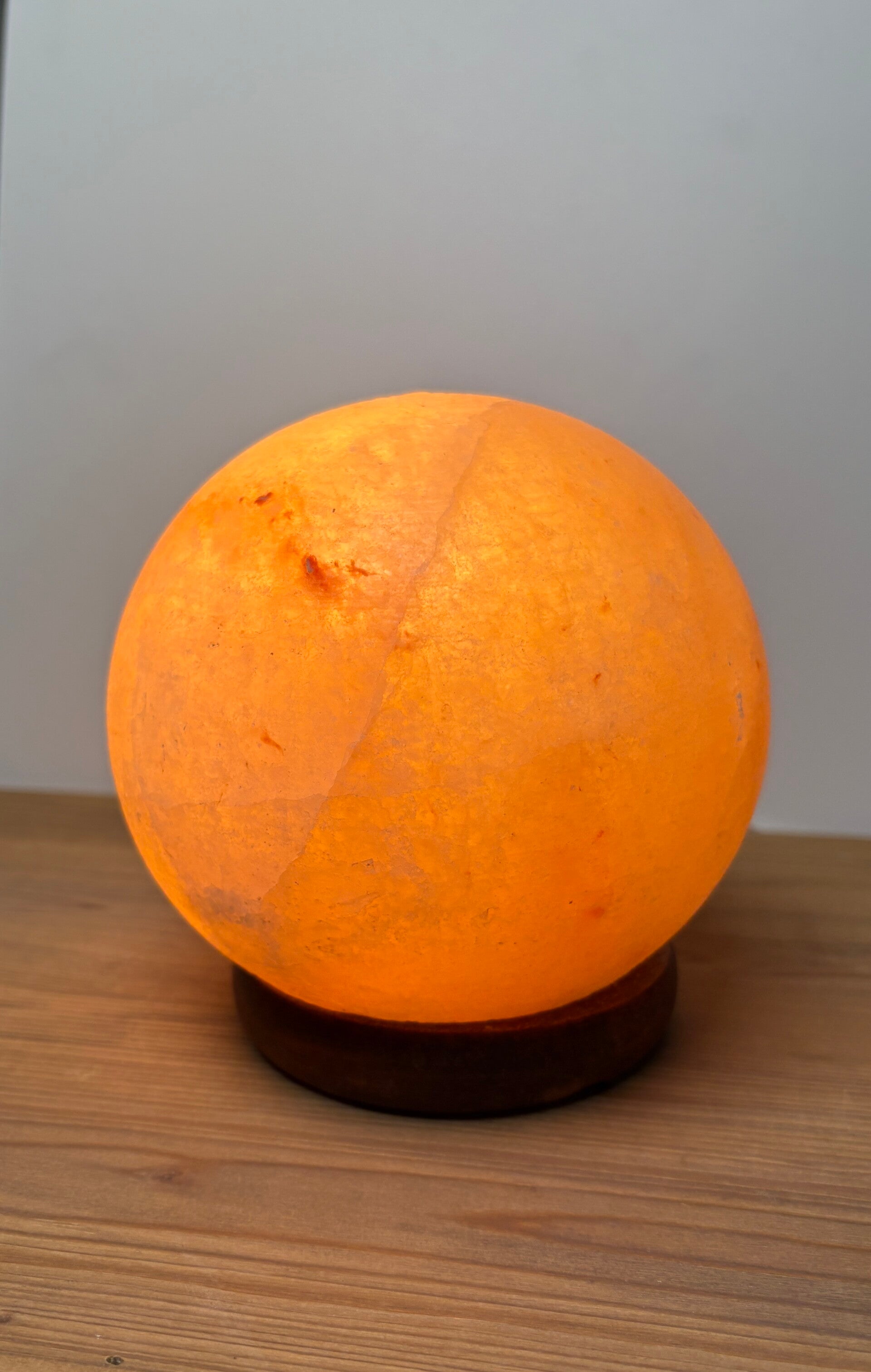 Kleine zoutlamp bol op donkere houten voet