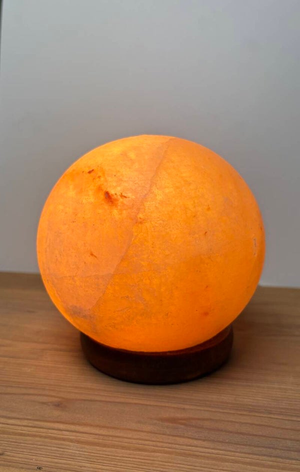 Kleine zoutlamp bol op donkere houten voet
