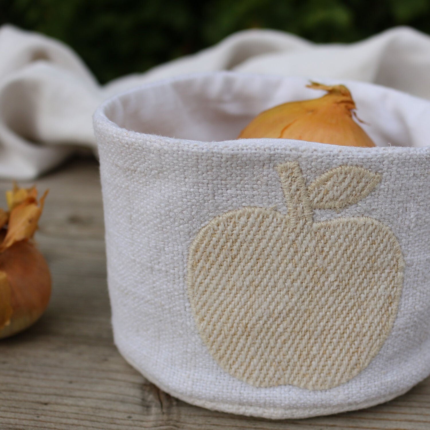 Panière en chanvre ancien avec appliqué pomme, accessoire de cuisine Pluie de Lin posé sur un plan de travail en bois.