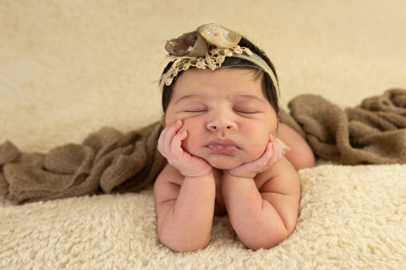 lief klein babymeisje met de handjes onder haar kin. 