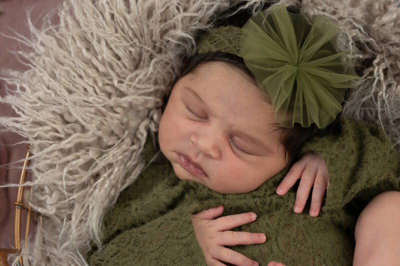 lief klein baby meisje met groene strik die lekker ligt te slapen