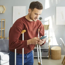 Young man at home on crutches, representing the value a Waiver of Premium rider adds to a life insurance policy in case of disability